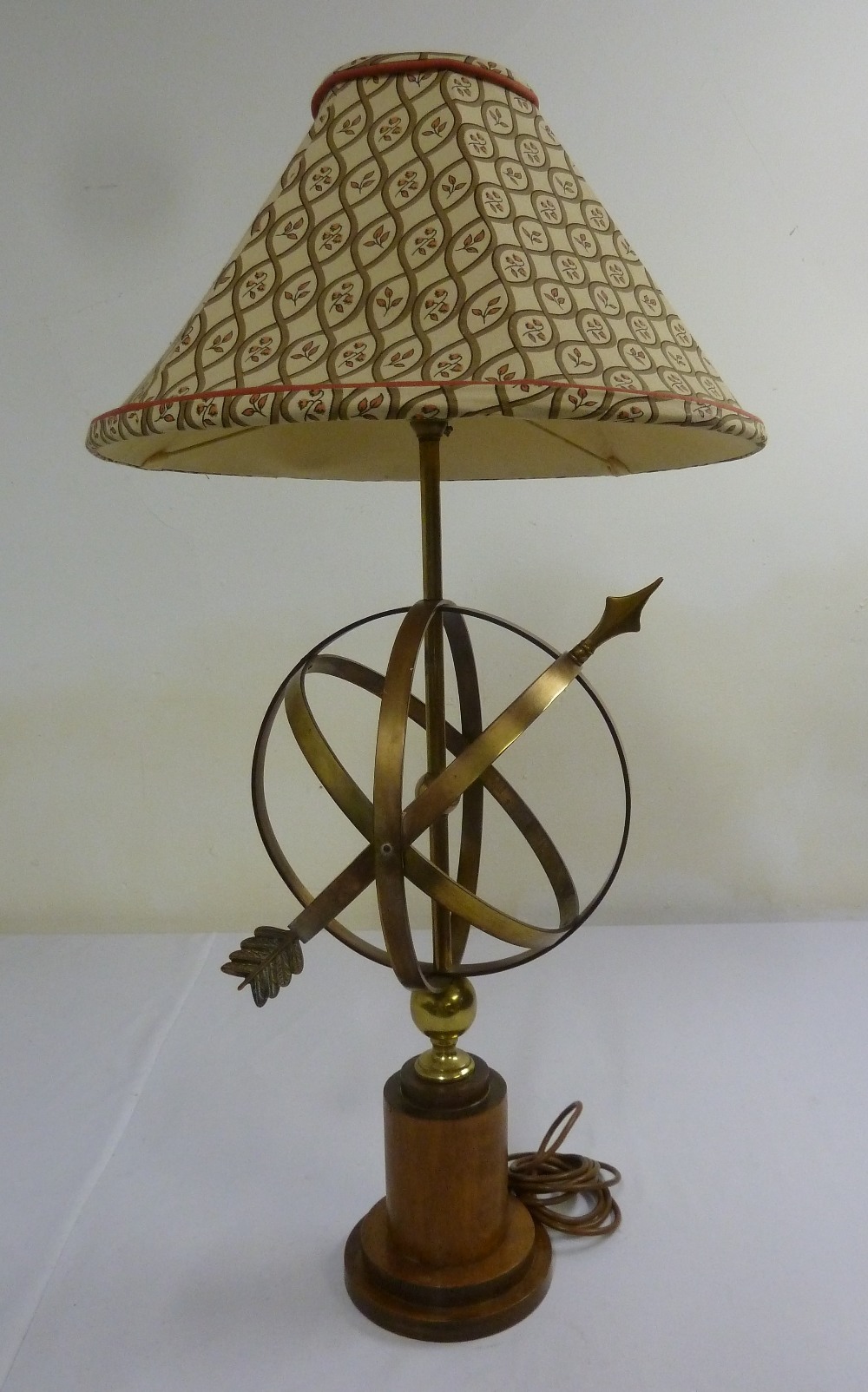 Brass table lamp in the form of a sundial on raised wooden stand with linen shade