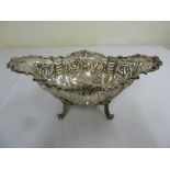 An Edwardian silver cake basket oval scroll pierced sides, applied floral and leaf border on four