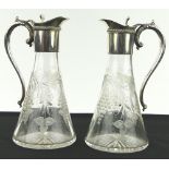 A pair of heavy cut-glass claret jugs with plated mounts.