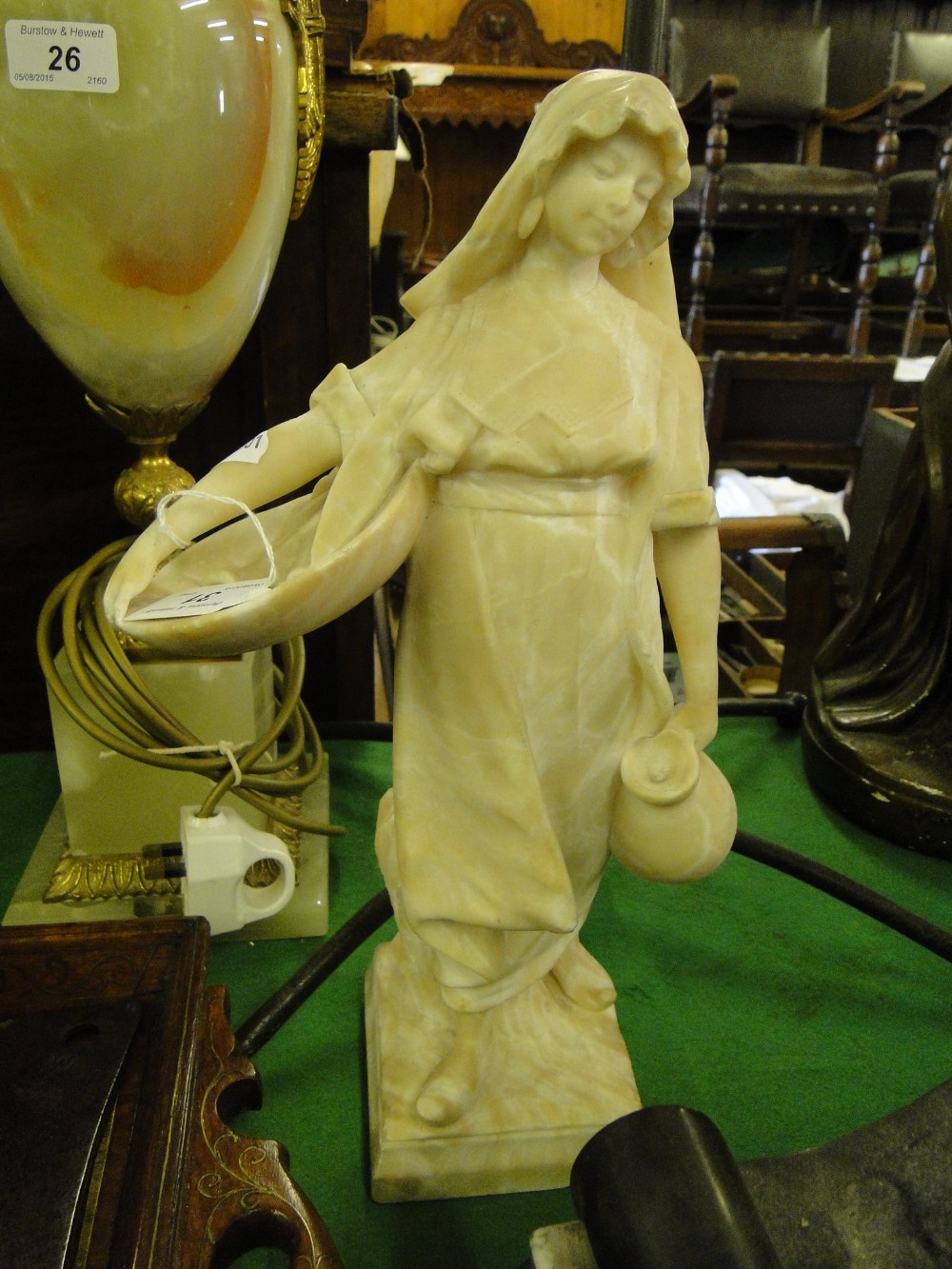 A carved alabaster girl with jug and dish.
