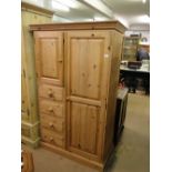 A modern pine wardrobe with fitted cupboard and drawers.