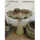 A weathered stoneware bird bath.