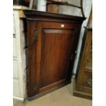 A George III oak hanging corner cupboard with panelled door.