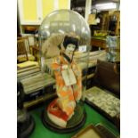 A Japanese silk doll under tall Victorian glass dome.