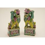 Pair of provincial Chinese Buddhist lions, brightly coloured in pink, yellow and terracotta glazes,