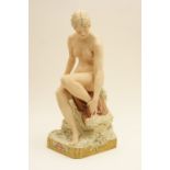 Royal Dux figure of a bathing nude seated on a rock, decorated in naturalistic colours,