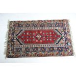 Hamadan woollen rug, red medallion within a wide fawn and blue border, size approx.