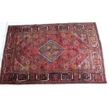 Persian Meimeh woollen rug, the central diamond medallion against a madder field,