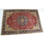 Tabriz woollen carpet, the central blue medallion against a deep red field,
