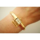 Baume & Mercier lady's 18ct gold bangle wristwatch, signed small rectangular dial with hinged cover,