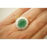 Emerald and diamond cluster ring in 14ct white gold, the oval cut emerald of approx 8.