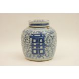 Provincial Chinese blue and white ginger jar and cover decorated with shou characters against a