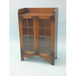 A solid, dark oak dwarf bookcase, single shelf enclosed by a pair of leaded glazed doors, 2ft. - one