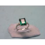 A white metal dress ring, large step-cut green stone, two small diamonds to each shoulder, size K,