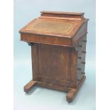 A Victorian walnut Davenport, sloping top with stationery fittings, four side drawers with turned