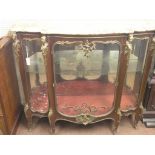 A large Louis XV-style mahogany display cabinet, serpentine-shape with elaborate ormolu mounts and