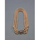 A three-row cultured pearl necklace, 9ct. white gold mount set small sapphires in rosette design