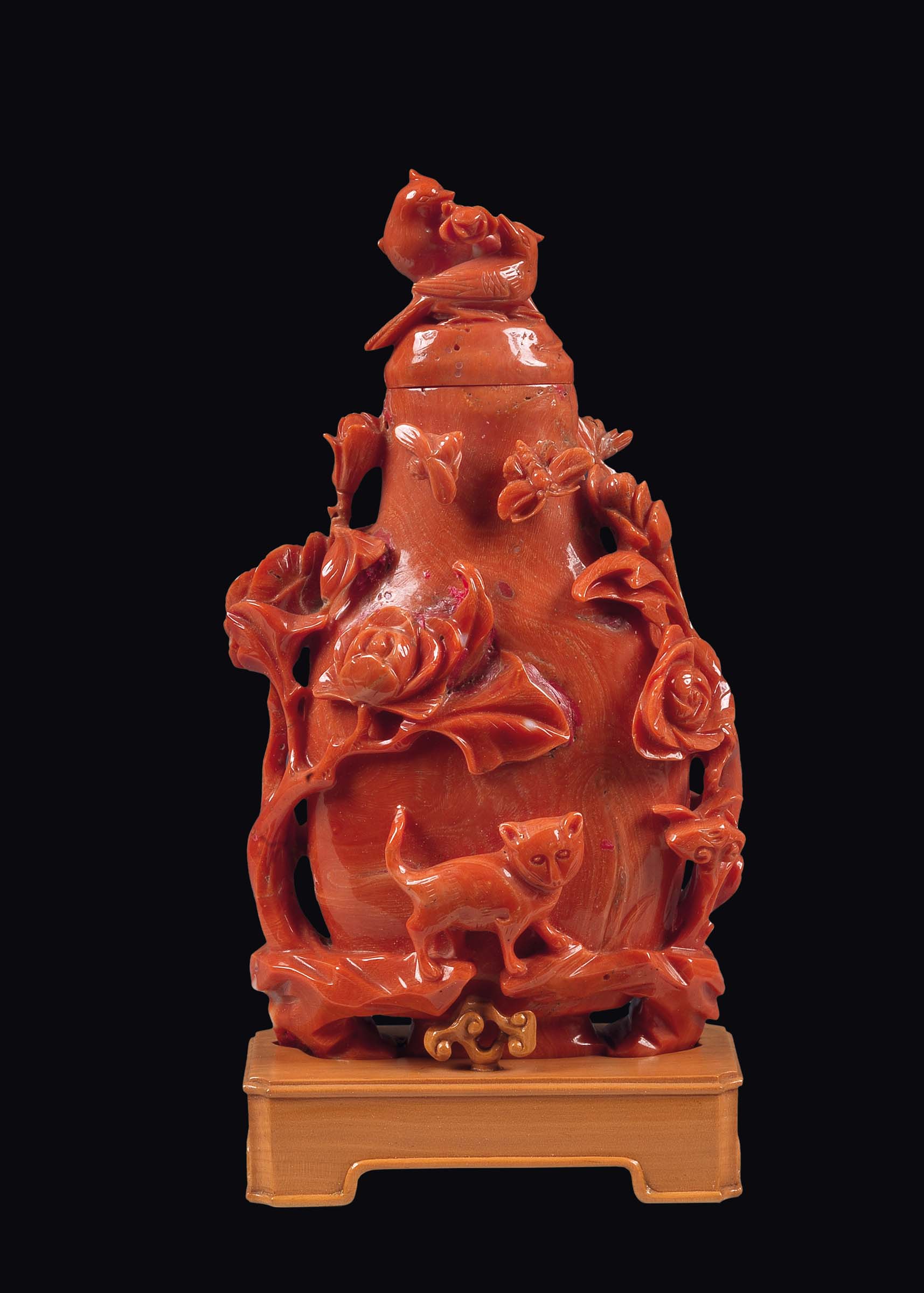 A carved coral vase and cover with birds and decoration of flowering branches, batterflies and a cat