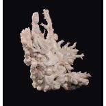 A carved white coral "Guanyin and children between branches and peaches" group, China, early 20th