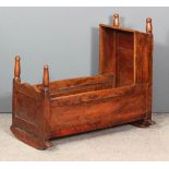 An 18th Century panelled elm rocking cradle with four turned finials, 34ins x 15.5ins x 31ins high