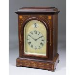 A late 19th Century German mahogany cased mantel clock, the arched silvered dial with Roman numerals