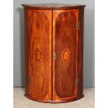 A George III mahogany bow-front hanging corner cupboard with narrow moulded cornice, fitted three