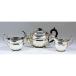 A George V silver three piece tea service of Georgian design with oval panelled bodies, with moulded