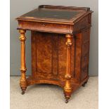 A 19th century French walnut Davenport with black cloth lined slope enclosing two small drawers,