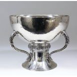 A George V hammered silver circular fruit bowl with three leaf capped and fluted handles, embossed