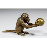 An early 20th Century Austrian gilt bronze figure of a monkey wearing spectacles and holding a skull