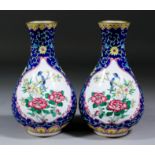 A pair of Chinese Cantonese enamel baluster shaped vases decorated with birds perched on flowering