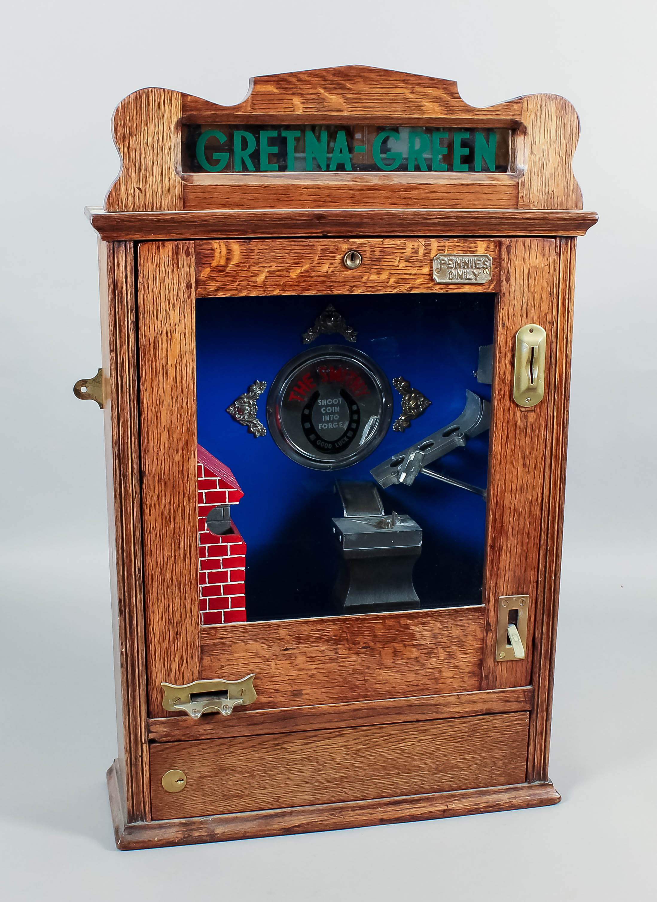 A modern replica oak cased penny-in-the-slot "Gretna-Green-The Smithy" penny flick machine with a