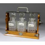 An early 20th Century chromed metal mounted oak three bottle "Betjeman's Patent" tantalus, 14ins