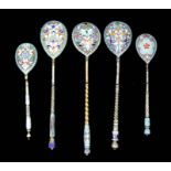 Five Russian silvery metal and champleve enamel tea spoons, the bowls enamelled with flowers and