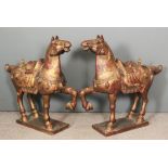 A pair of Eastern carved and giltwood figures of horses, each with one raised front leg, on