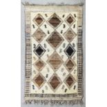 A North African rug woven in blue and brown with lozenge motifs on a cream ground within