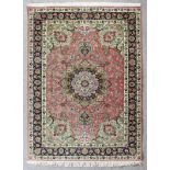 A modern Tabriz rug woven in colours with a bold central floral filled medallion and conforming