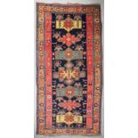 An antique Karabagh carpet woven in muted colours with seven geometric medallions on a dark blue