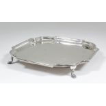 A George V plain silver square salver of early 18th Century design, the shaped rim with leaf