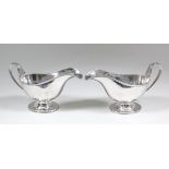 A pair of George V silver oval sauce boats with reeded mounts to rim and loop handles, conforming