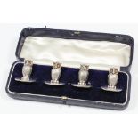 A set of four Edward VII cast silver menu holders each in the form of an owl with glass eyes on