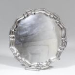 A George V plain silver circular salver with moulded rim and on three scroll feet, 8ins diameter, by