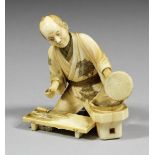 A Japanese carved ivory figure of a seated fishmonger, 2.5ins (64mm) high (red seal mark - Meiji