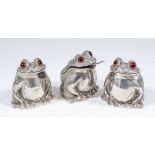 An Elizabeth II cast silver three piece cruet set, modelled as seated toads, each with glass eyes,