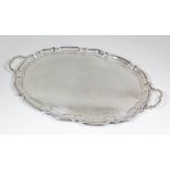 A George V silver oval two-handled tray with moulded piecrust rim, 23.5ins x 15.25ins, by Cooper