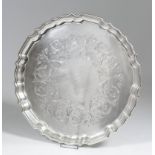 A Canadian silvery metal circular salver with shaped and moulded rim and engraved with a band of