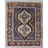 An Afshar rug, woven in blue, tan and ivory with double lozenge medallion, and filler motifs on a