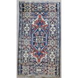 An antique Brojerd rug woven in muted colours and ivory with lozenge shaped medallion within wide