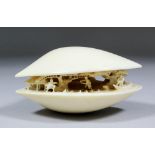 A Japanese ivory carved as a shell, the interior with figures in a landscape, 4ins (102mm) x 3ins (