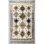 A North African rug woven in blue and brown with lozenge motifs on a cream ground within